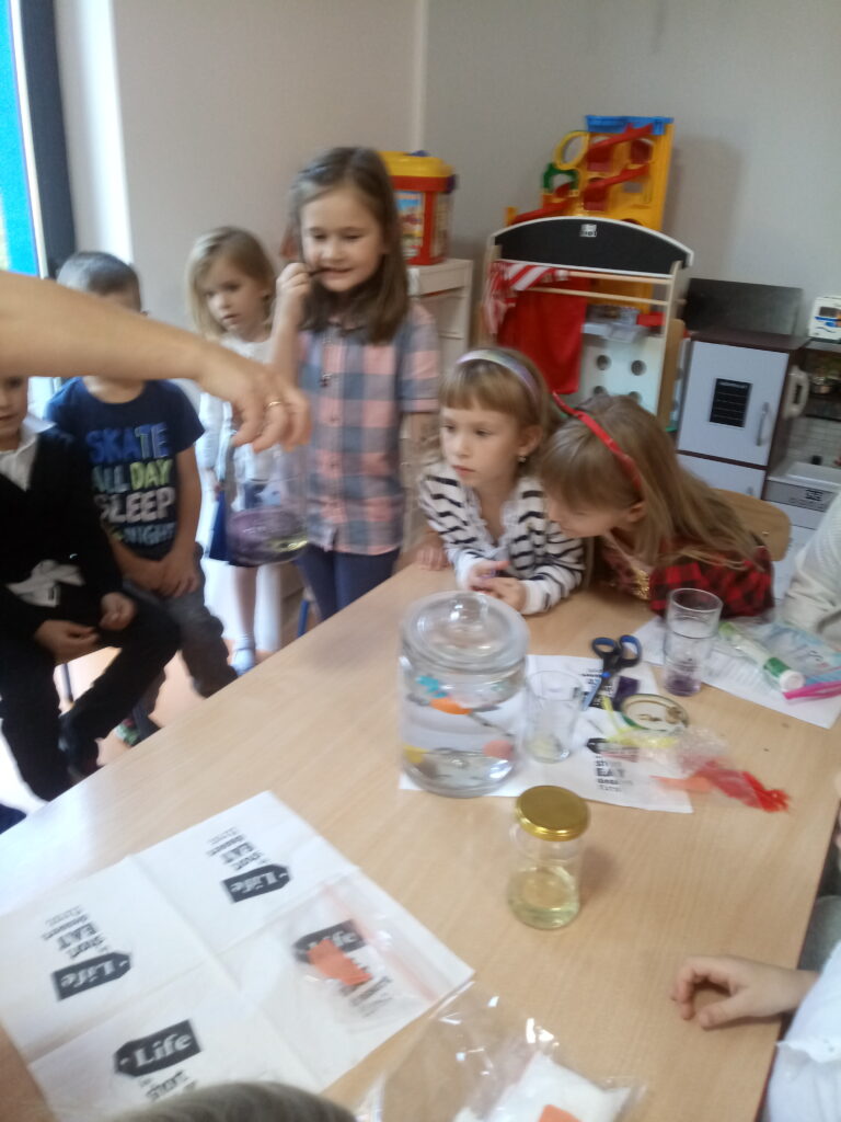 grupka dzieci robi eksperymenty z wodą
